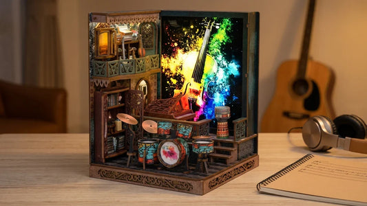 Le Studio de Musique monté et allumé sur un bureau en bois, avec son piano à queue, sa batterie colorée et son mur lumineux, à côté d'un casque audio, d'un carnet de musique à spirale et d'une guitare acoustique posée contre le mur