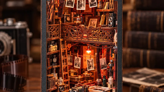 Book nook Chambre Noire éclairé, laboratoire photo miniature entre des livres, à côté d'un appareil photo ancien : une idée de cadeau à construire pour un homme de 30 ans