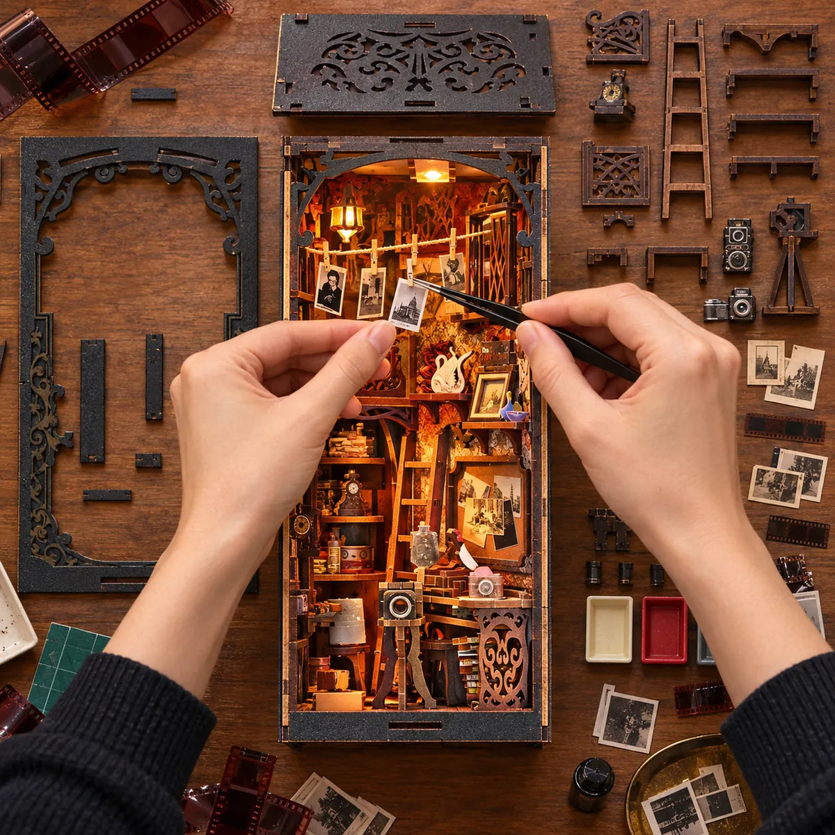 Montage de La Chambre Noire vu du dessus avec mains et tirages miniatures