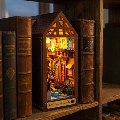 Book nook Maison de Colmar glissé entre deux livres dans une bibliothèque, lumière chaude