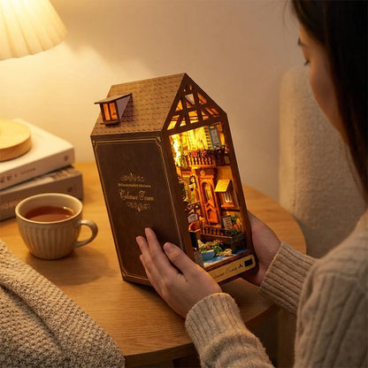 Femme tenant le book nook Maison de Colmar allumé dans ses mains, moment cosy le soir sans écran