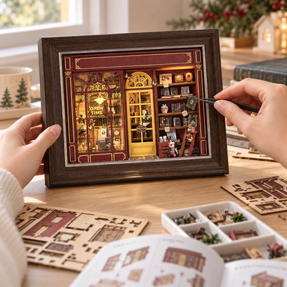 La Librairie du Soir NOOKO — Deux avant-bras assemblent le book nook avec une pince de précision, vu à hauteur de table.