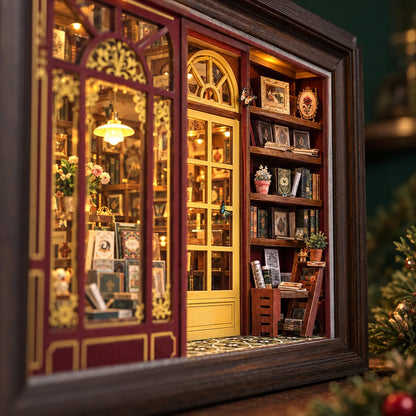 La Librairie du Soir NOOKO — Vue immersive en diagonale à travers la vitrine éclairée vers la porte et les rayonnages miniatures.
