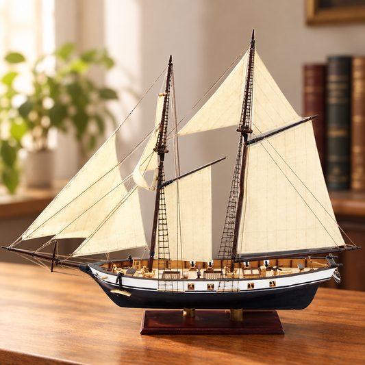 Maquette de goelette en bois assemblee sur son socle, posee sur un bureau