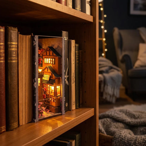 Kit book nook Ruelle de Kyoto en bois, lanternes allumées, posé entre des livres sur une étagère