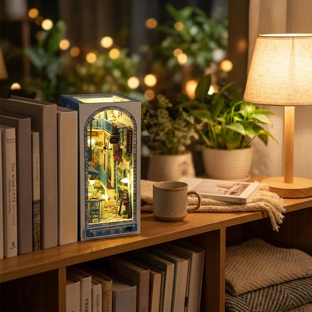 Book nook Ruelle de Santorin dans un salon cosy le soir, ambiance chaleureuse et plantes vertes